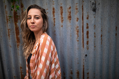 Portrait of young, woman in front of garage on the street, looking at camera, seriously