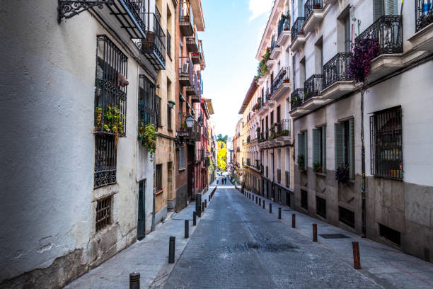 Colourful apartment blocks and iron balconies line a narrow side street in the Lavapies district of Madrid, Spain.