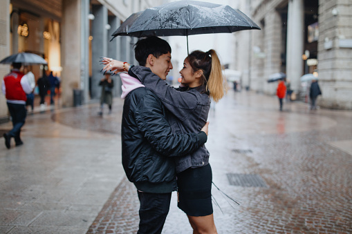 Boyfriend embracing his girlfriend under an umbrella