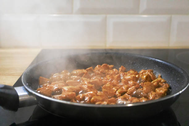istock Chicken fillet fried in black pan at the home kitchen with selective focus. Smoke cooking 1194478334