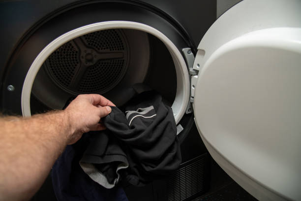 istock pulling clothes out of a condenser tumble dryer 1194478669