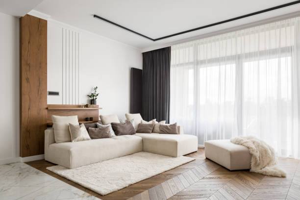 Elegant and comfortable living room Elegant and comfortable designed living room with big corner sofa, wooden floor and big windows carpet cushion stock pictures, royalty-free photos & images