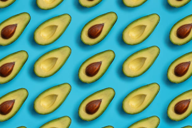 istock Summer food pattern. Avocado halves on blue background. Top view. Flat lay 1194479547