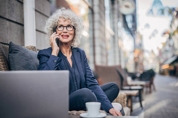 starsza pani rozmawia na mobilnych zewnątrz w kawiarni - sidewalk cafe cafe stockholm sweden zdjęcia i obrazy z banku zdjęć