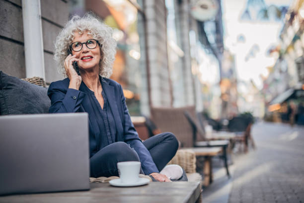 starsza kobieta rozmawia na telefon komórkowy na zewnątrz w kawiarni - sidewalk cafe cafe stockholm sweden zdjęcia i obrazy z banku zdjęć