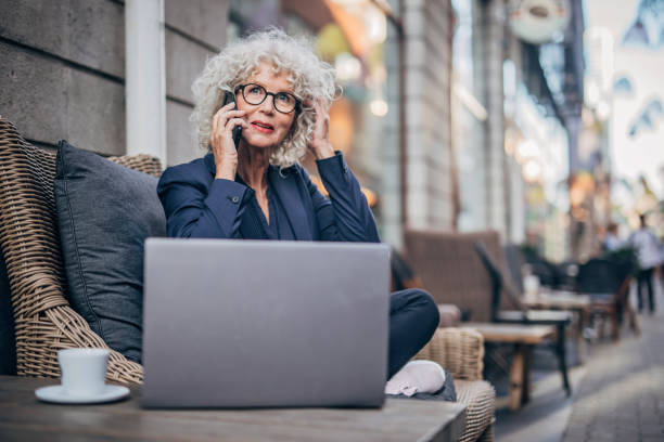 istock Beautiful senior lady talking on mobile outdoors in cafe 1194482042