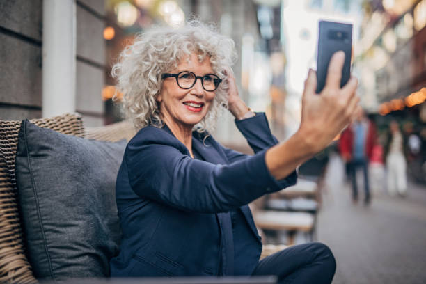 starsza kobieta mówi selfie na świeżym powietrzu w kawiarni - sidewalk cafe cafe stockholm sweden zdjęcia i obrazy z banku zdjęć