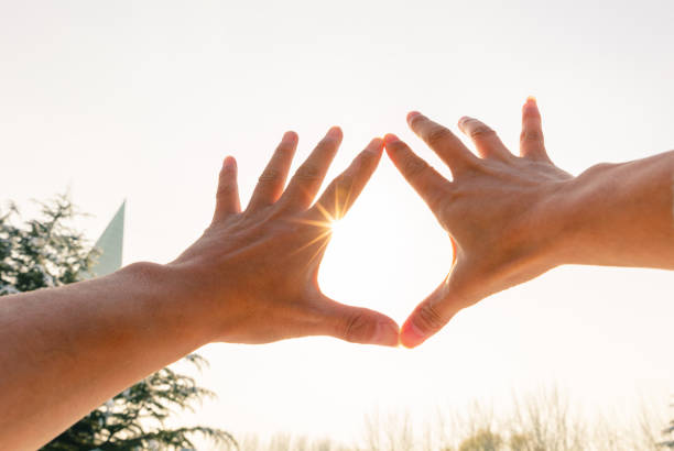 istock hands forming a heart shape with sunset silhouette. 1194483929