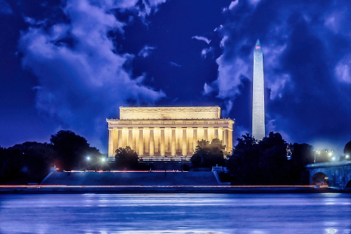 Long Exposure of Lincoln and Washington Monuments at night with beautiful clouds and Potomac River in Washington DC