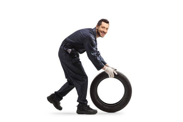 istock Auto mechanic rolling a car tire 1194486379