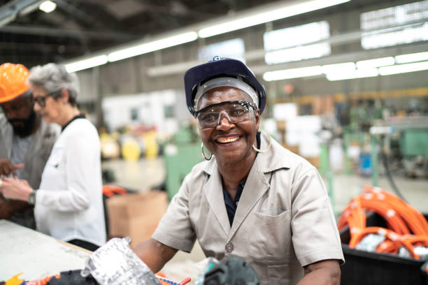 Happy and dedicated senior employee working in a factory Happy and dedicated senior employee working in a factory womens rights photos stock pictures, royalty-free photos & images