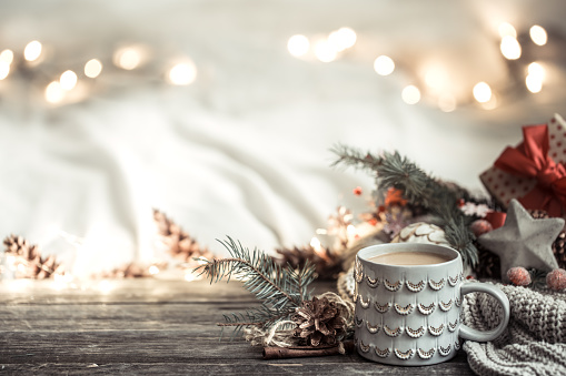 Festive background with Cup on wooden background with lights and festive decor. Coziness and comfort at home. The concept of the new year holiday.