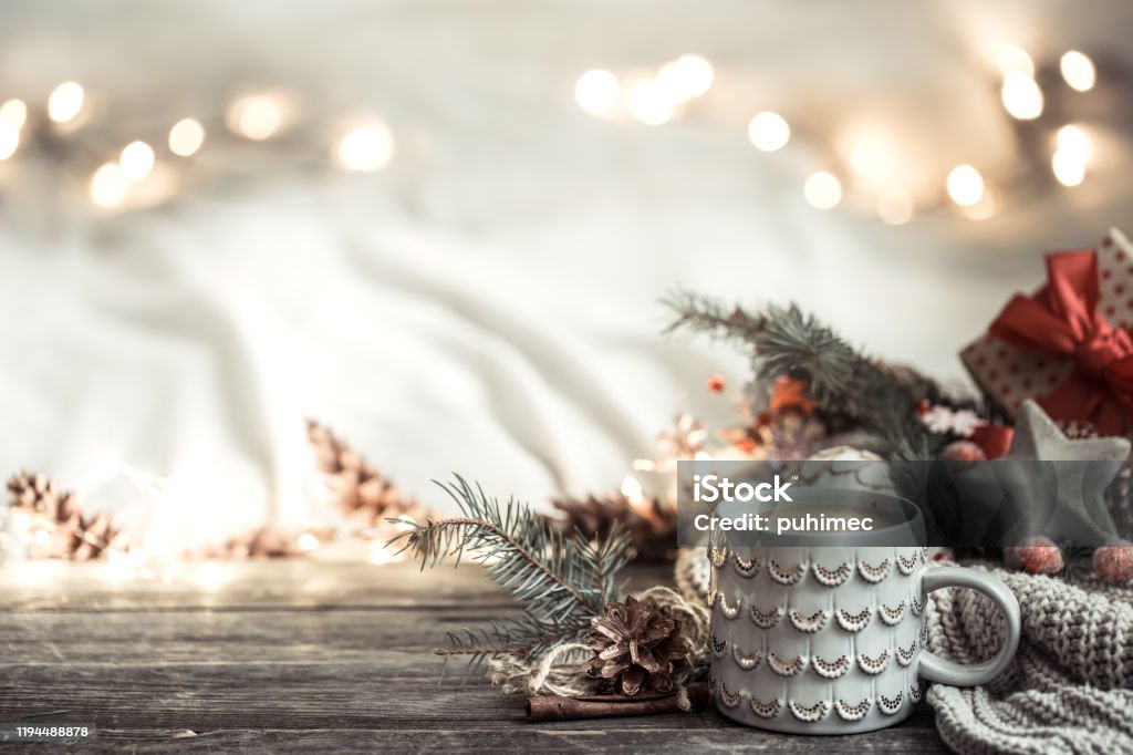 Festive background with Cup on wooden background with lights. Festive background with Cup on wooden background with lights and festive decor. Coziness and comfort at home. The concept of the new year holiday. Vacations Stock Photo