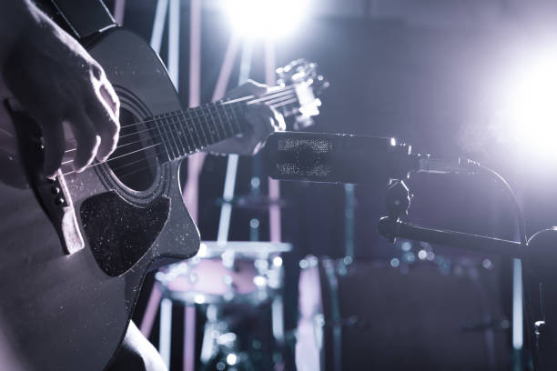 The Studio microphone records an acoustic guitar close-up. Beautiful blurred background of colored lanterns. The Studio microphone records an acoustic guitar close-up, in a recording Studio or concert hall, with a drum set on a background in out-of-focus mode. Beautiful blurred background of colored lanterns chord photos stock pictures, royalty-free photos & images