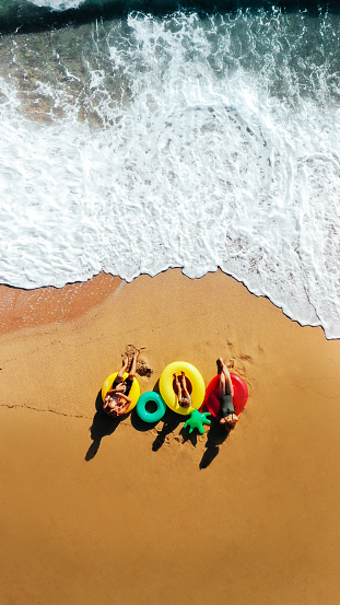 Photo of a happy family on the beach, sitting on inflatable rings