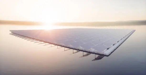 Photo of Aerial image of  floating solar power plant farm on calm lake  in beautifull sunset sunlight with misty forest landscape and cloudy sky in background. 3d rendering.