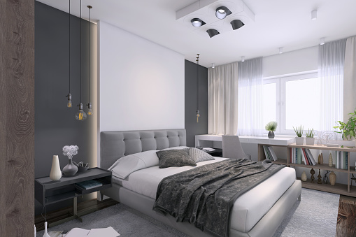 Modern bedroom interior with large pastel colored bed and pillows with big blank white wall for copy space in the background. Window, shelves, table, chair, electric lamp and plant. Render.