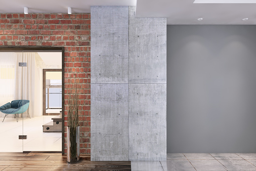 Contemporary apartment interior with big grey wall for copy space and concrete textured pillar and brick wall with living room in the background. Render.