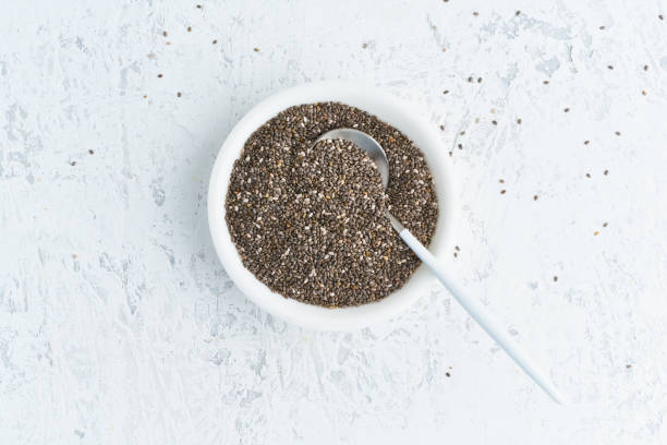 Chia seeds in white bowl on white stone concrete background, top view, copy space Chia seeds in white bowl on a white stone concrete background, top view, copy space chia seed photos stock pictures, royalty-free photos & images