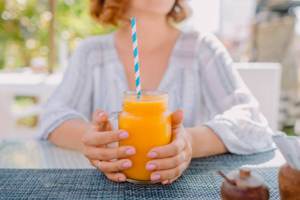 istock Woman and fresh orange juice with straw on table 1194497053