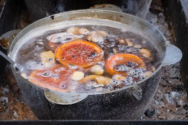 Photo of Hot spiced wine made with red wine in large copper pot Christmas food street market