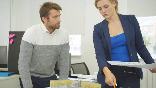 istock Engineer with scheme in hand discuss project of houses with workmate 1194499885