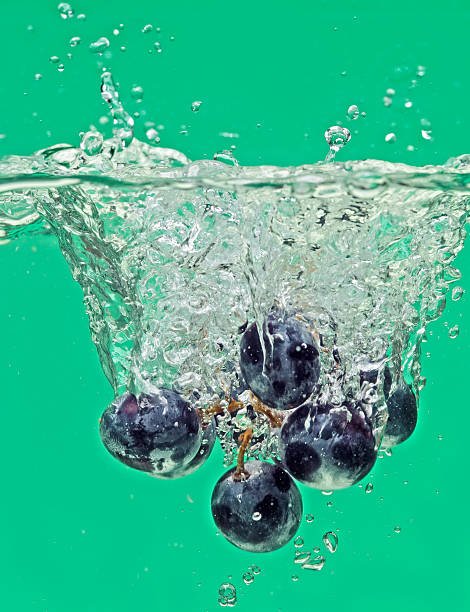 Bunch of grapes floating in water with air bubbles stock photo