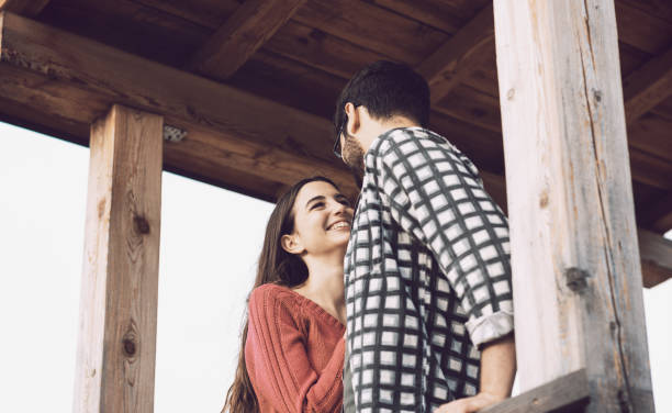Romantic loving couple staring at each other in a wooden gazebo, feelings and relationships concept