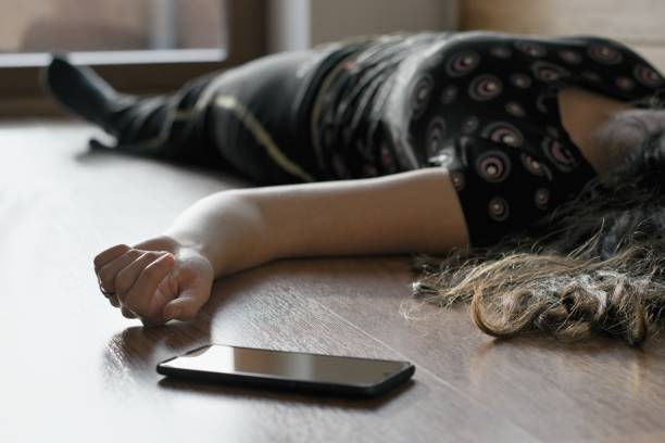 у женщины, лежащей дома на полу, телефон упал рядом с ее рукой. - human hand help pain heart attack стоковые фото и изображения