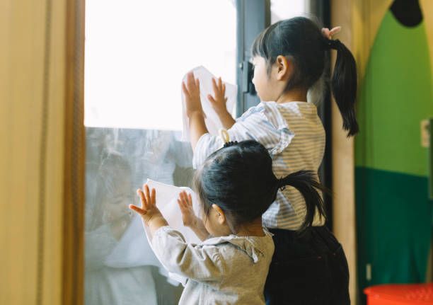 二人の小さな女の子が窓を掃除 - 年末 ストックフォトと画像