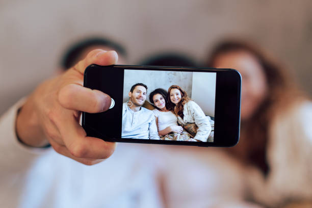 istock Girl and her parents taking a selfie while enjoying on the sofa 1194505362