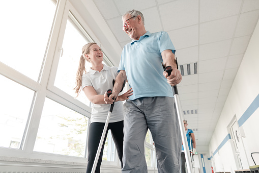 Personas mayores en rehabilitación aprenden a caminar con muletas photo