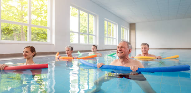 femmes et hommes dans des exercices d'eau pendant la remobilisation - water aerobics swimming pool exercising sport photos et images de collection