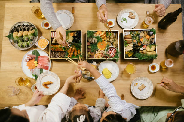 Hands reaching for food on New Year's Eve Dinner table