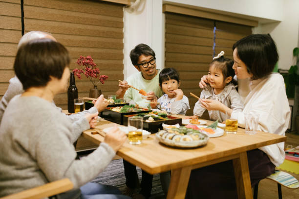 Celebrating on New Year's Day Three generation family celebrating on New Years eve. Osechi Ryori - a traditional Japanese food on the table. baby new years eve new years day new year stock pictures, royalty-free photos & images