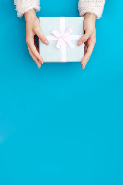 istock Photo with female hands and a gift on a turquoise background. 1194511607