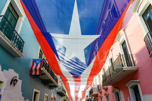 Puerto Rican Flag Over Calle La Forteleza in Old San Juan In Old San Juan a large Puerto Rican flag covers the ope of Calle Forteleza leading to the Governor’s Mansion. puerto rican culture stock pictures, royalty-free photos & images