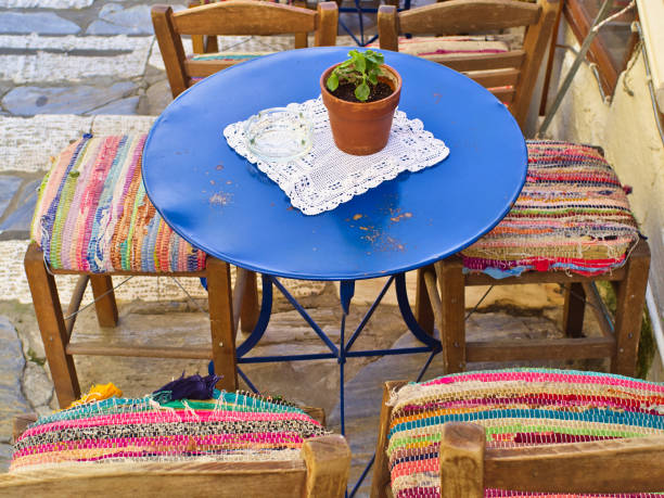 Plaka, Athens, cafe blue table with rustic doily cover with lace and colorful chairs with traditional textile.