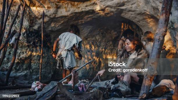 Tribe Of Huntergatherers Wearing Animal Skin Live In A Cave Leader Brings Animal Prey From Hunting Female Cooks Food On Bonfire Girl Drawing On Wals Creating Art Neanderthal Homo Sapiens Family Stock Photo - Download Image Now