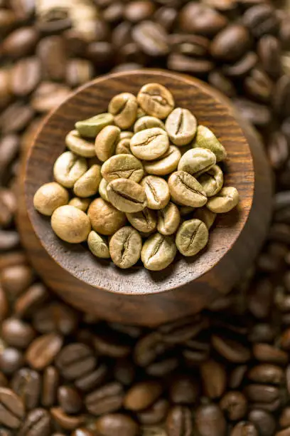 Wooden Jar Fill With Green Coffee Beens. Surrounded Roasted Coffee Beens.