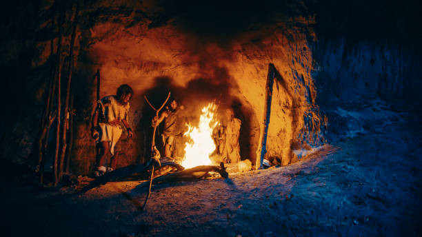 stamm der prähistorischen jäger-sammler tragen tierhäute stehen um bonfire außerhalb der höhle in der nacht. porträt von neandertaler / homo sapiens familie tun heidnischen religion ritual in der nähe von feuer - outdoor fire fotos stock-fotos und bilder