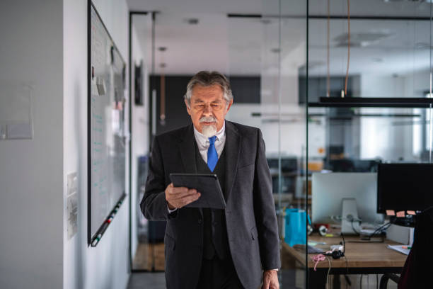 istock Senior businesman using digital tablet in the office hall 1194517411