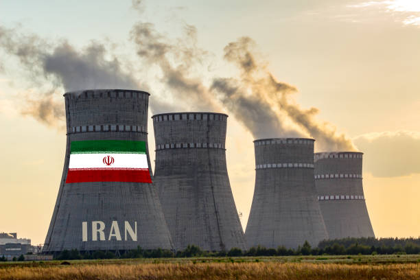Nuclear plant chimneys displaying flag of Iran with according text. Energy pollution accidents in a country concept. stock photo