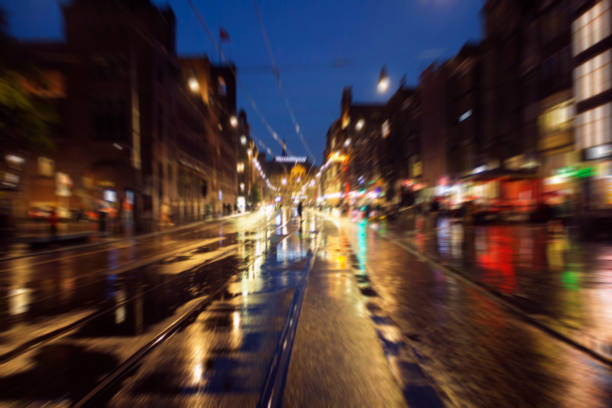 Blurry motion image Damrak avenue in Amsterdam. It is a rainy summer night.