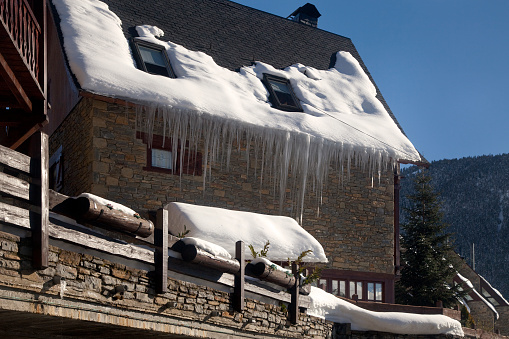 Horizontal view of a mountain house with some icicles hanging from its roof, Salardú, Vall d’Aran, Lleida, Catalonia