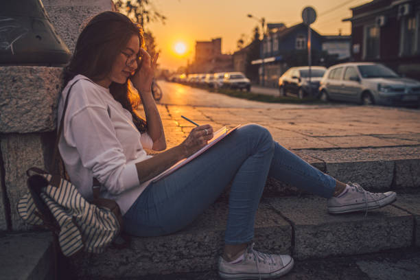 istock Carefree student writing in notepad outdoors in sunset 1194523006