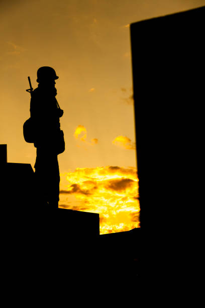 istock Soldier in silhouette looking at golden sky. 1194528532