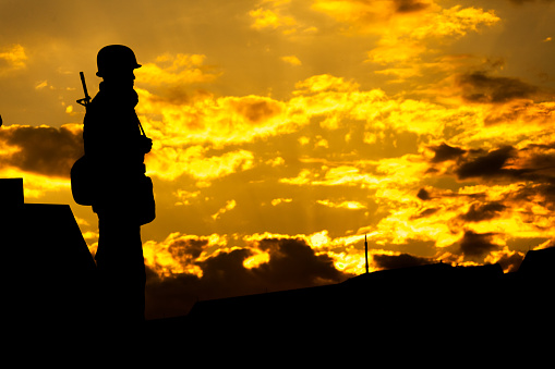 Soldier in silhouette looking at golden sky.