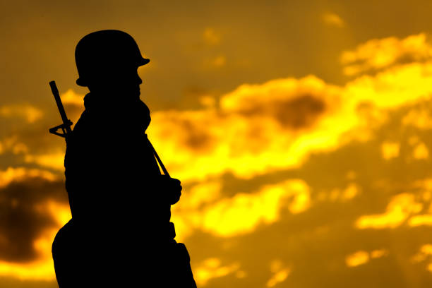 Soldier in silhouette looking at golden sky.