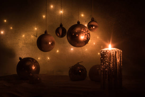 Christmas decoration with burning candles on a dark background. Christmas ornaments over dark golden background with lights. Creative artwork decoration.